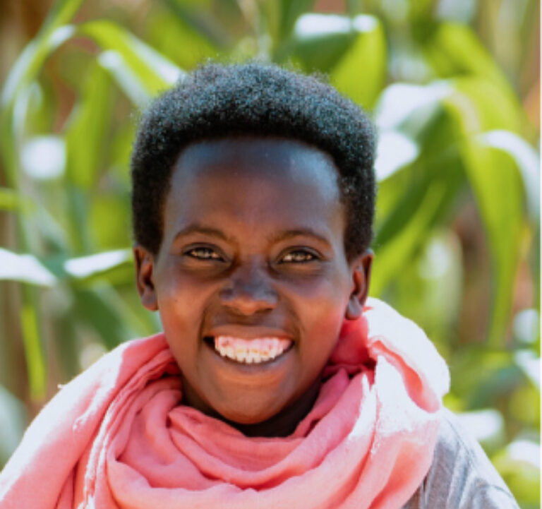 A girl wearing pink scarf smiling to the camera